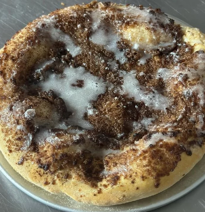 A cinnamon roll is sitting on top of a plate.